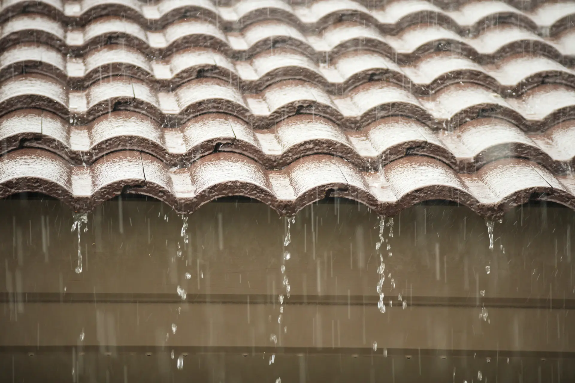 Rainwater streaming from a pantiled roof edge during an emergency inspection