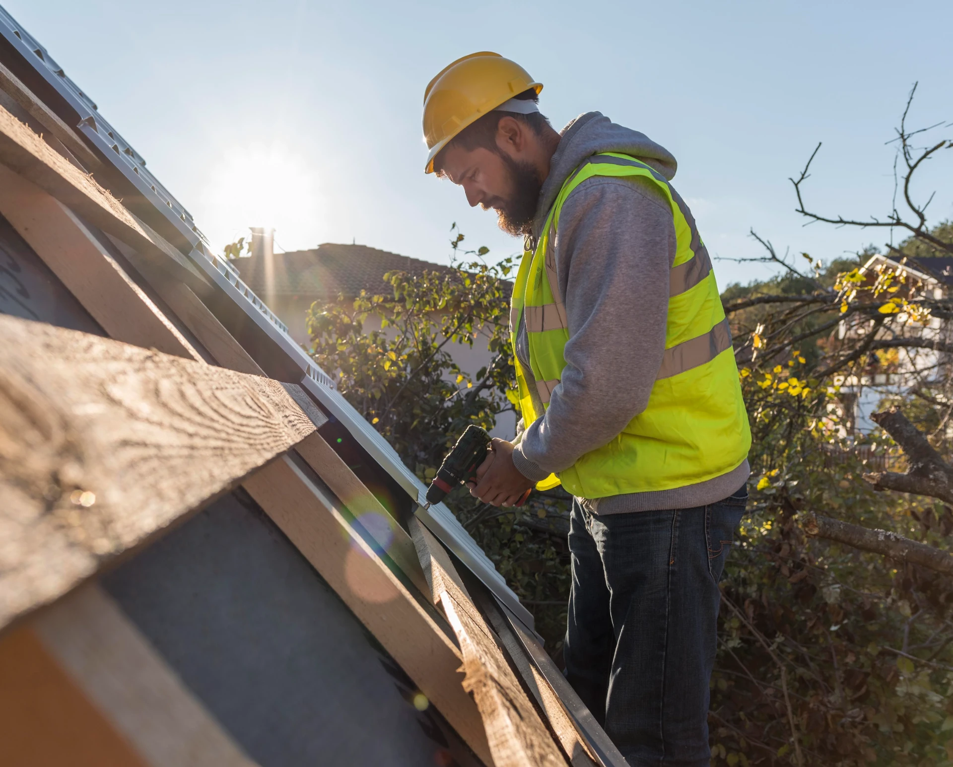 Roofer fixing new roof trim at the eaves with a cordless drill